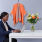 Black African woman in office with orange shawl hanging and flowers on desk